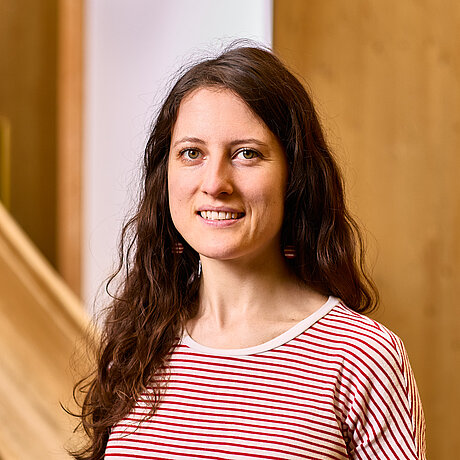 Portrait einer braunhaarigen Frau. Sie steht vor der Holzrutsche im NAWAREUM.