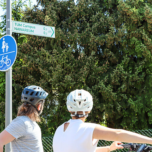 Zwei Radfahrer betrachten auzf einem Fuß- und Radweg einen Wegweiser zum NAWAREUM
